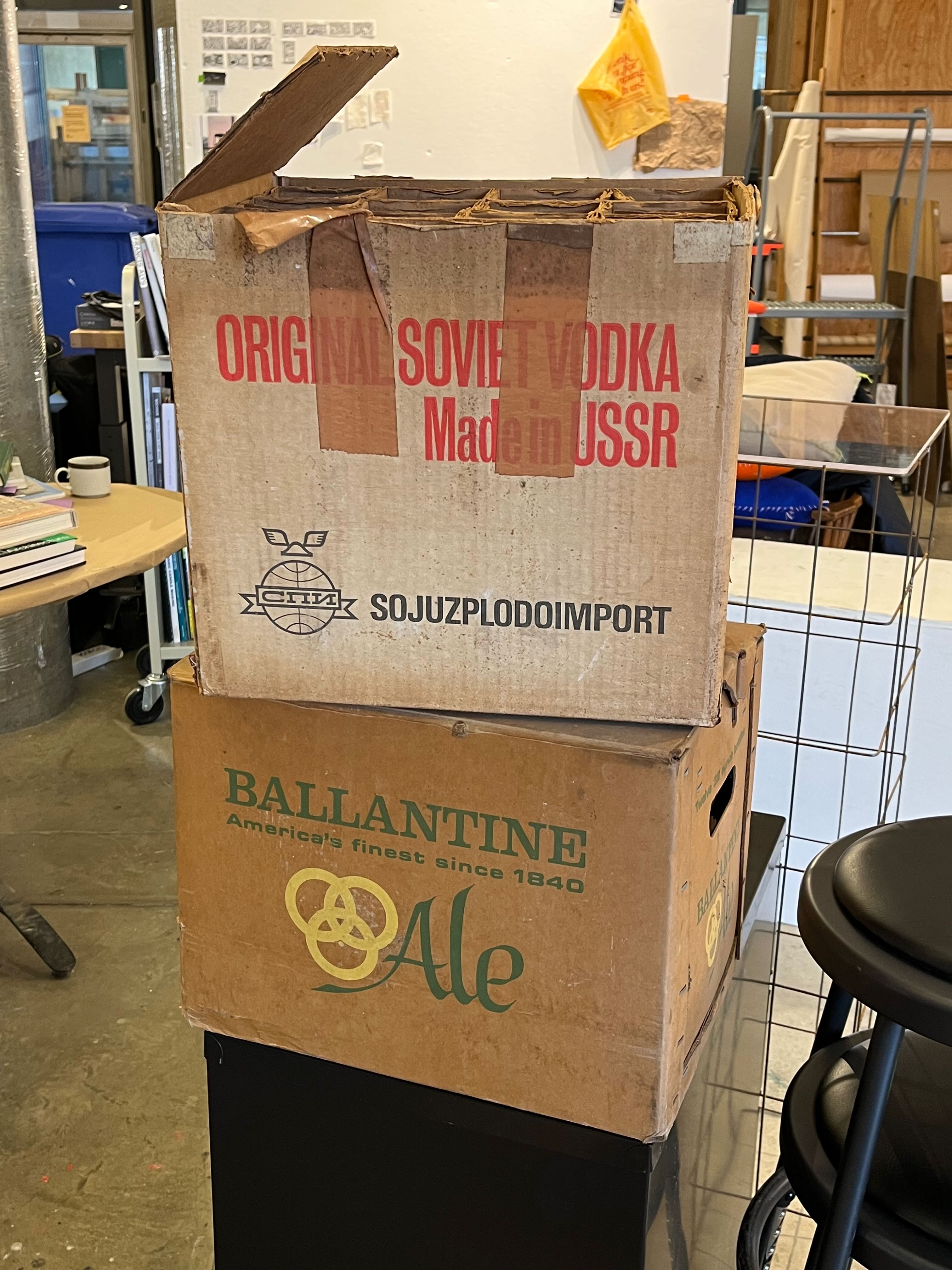 Image of two cardboard boxes, the top one saying ORIGINAL SOCIET VODKA Made in USSR and the bottom one reading BALLANTINE Ale America's finest since 1840
